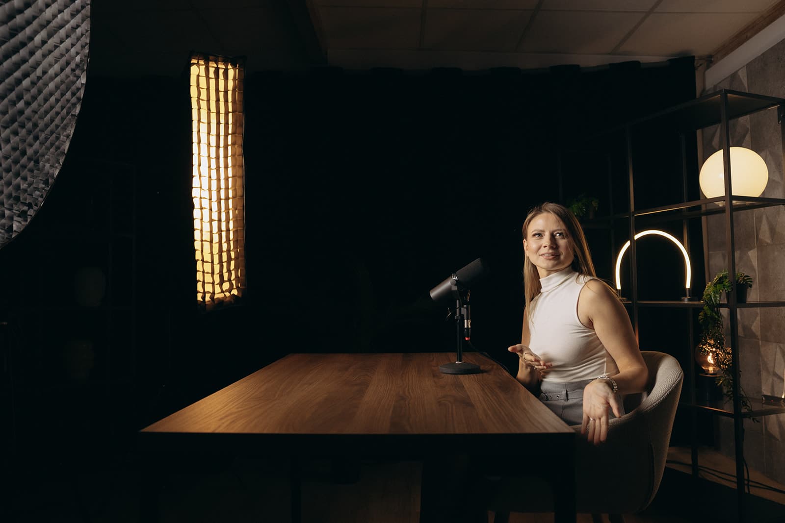 Hostka przy długim stole w studiu Odra Talks, ciepłe światło softboxu